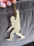 Charger l'image dans la visionneuse de la galerie, A delightful handmade ornament featuring a sasquatch design, crafted with resin on wood for a unique holiday decoration.