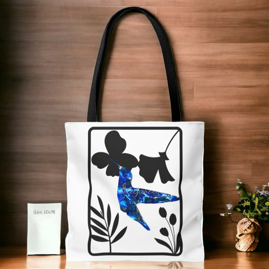 Blue Hummingbird with Modern Black Flowers Tote Bag displayed against a stylish wooden background, featuring an original art print design with a handmade resin hummingbird surrounded by black floral motifs.