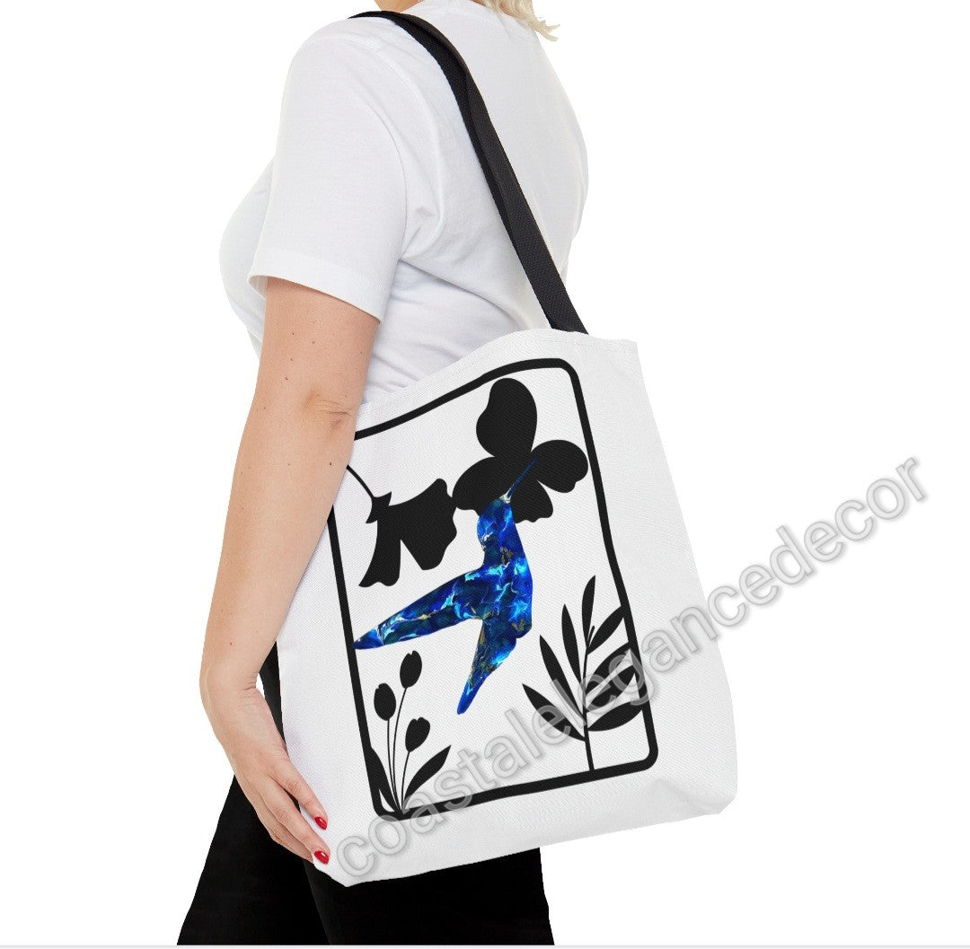 Woman carrying the Blue Hummingbird with Modern Black Flowers Tote Bag, highlighting the vibrant blue hummingbird artwork and elegant faux flower design in a practical and stylish format.