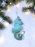 Charger l'image dans la visionneuse de la galerie, Blue handmade seahorse ornament with Christmas boughs and lights.