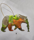 Charger l'image dans la visionneuse de la galerie, Handmade Grizzly Bear Christmas Ornament with Salmon - Rustic Wildlife Cabin Decor featuring a colorful resin overlay and metallic accents.