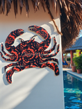 Load image into Gallery viewer, Weatherproof acrylic sea crab in patterns of orange and deep blue swirls hanging on a patio wall by the pool.