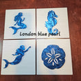 Load image into Gallery viewer, Four wall decor tiles with blue mermaid, seahorse, and sand dollar designs on a wooden surface.