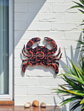 Load image into Gallery viewer, small outdoor acrylic crab hanging on white brick wall in orange and deep blue swirl patterns
