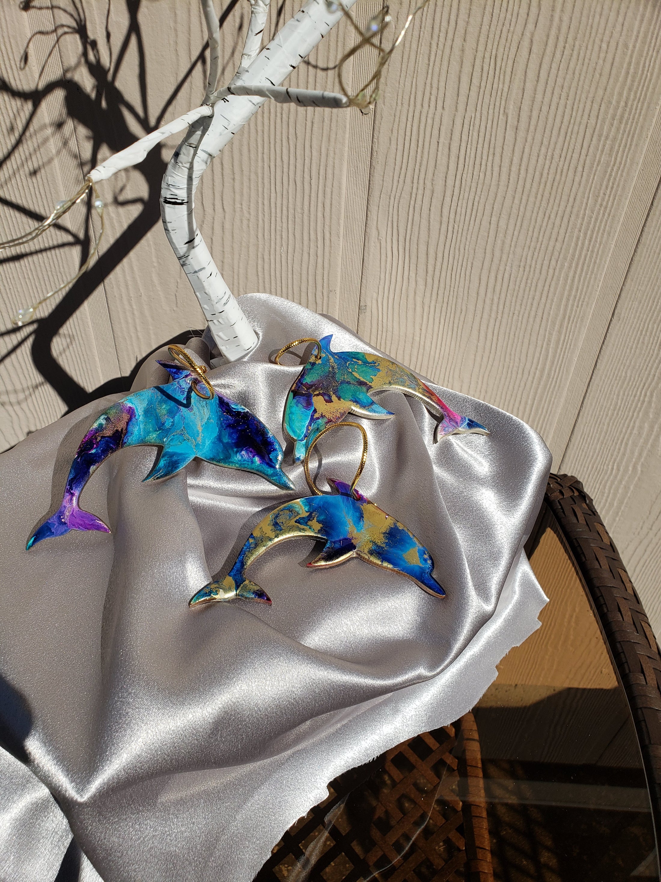 Close-up view of a unique ocean-themed Christmas tree ornament, showcasing handmade resin on wood with glittery details and a lifelike dolphin design.