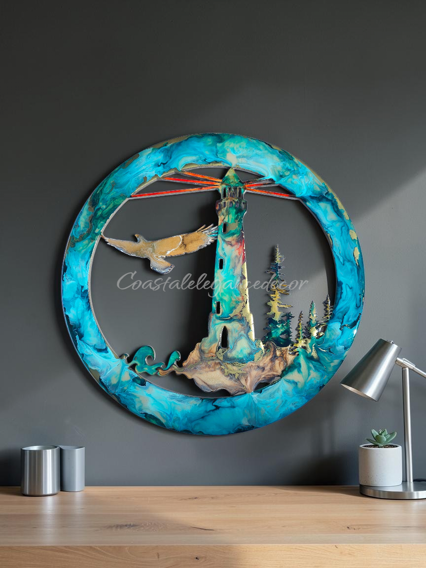 A circular 3D metal wall art piece featuring a lighthouse, trees, a bird, and abstract blue marbled borders, displayed on a wooden table against a dark gray wall with a lamp and small containers nearby.