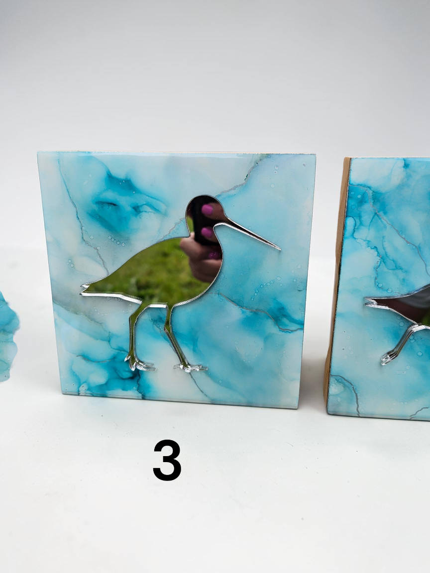 A square decorative tile featuring a mirror bird figure with a blue and turquoise marbled background, shown on a white surface with a black number 3 below it.