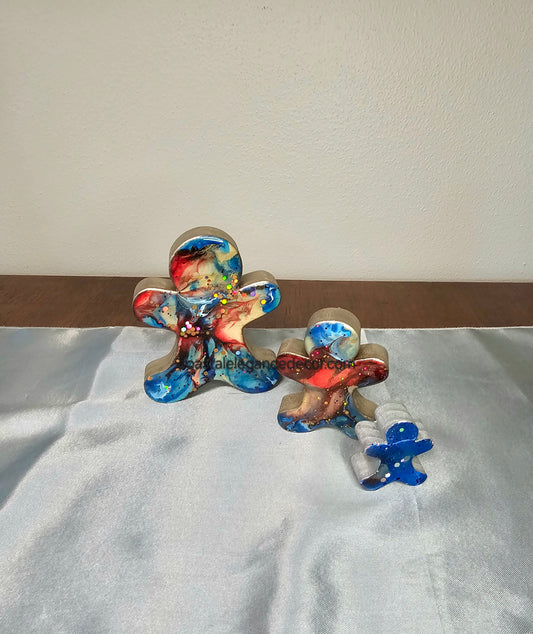 Handmade Gingerbread Men Christmas Decorations in blue and red chunky wood with resin, featuring three sizes on a silver background. Unique holiday decor piece for Christmas collection.
