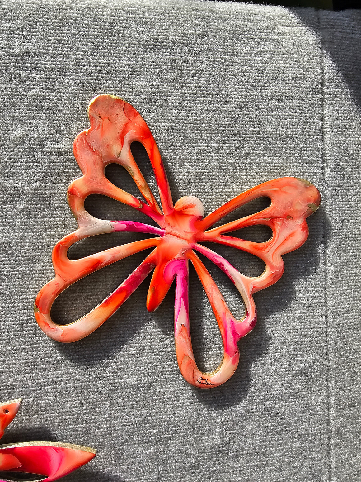 Colorful handmade butterfly wall decoration made of handmade resin on wood, featuring bold colors with silver shimmer.