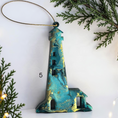 Charger l'image dans la visionneuse de la galerie, Teal handmade lighthouse resin and wood ornaments on a white background with Christmas lights and boughs 
