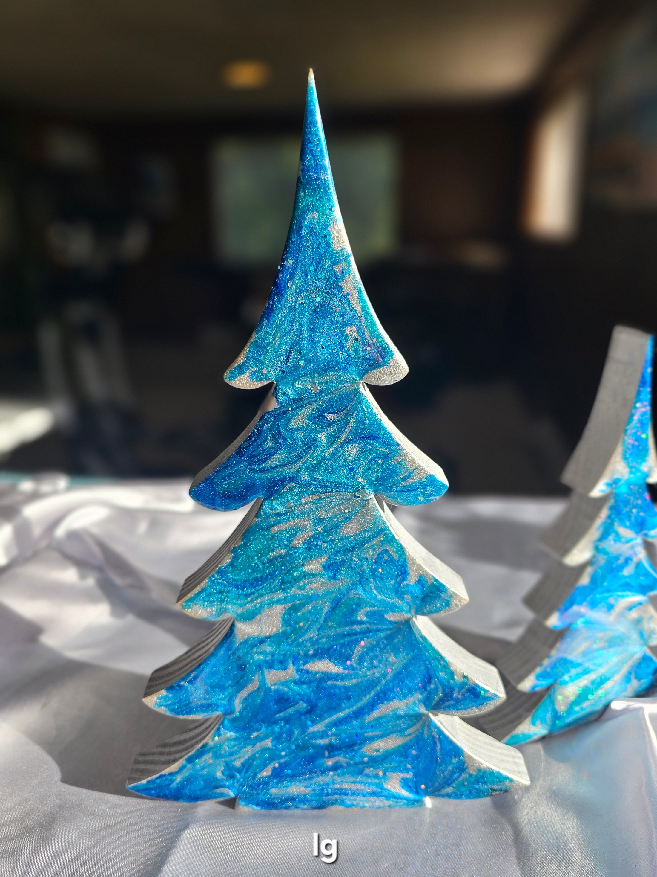 Close-up of Handmade Blue and Silver Resin Christmas Trees Holiday Mantelpiece with sparkling glitter accents.