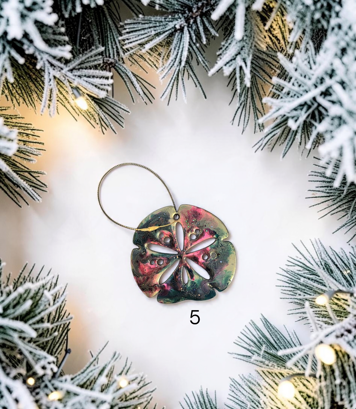 Multicolor handmade resin sand dollar ornament with gold hanger and white background.