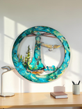 Load image into Gallery viewer, A circular wall art piece featuring a turquoise and teal lighthouse scene with a bird in flight, displayed above a wooden desk in a bright room.
