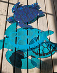 Load image into Gallery viewer, Close-up of a large transparent teal sea turtle showing the 1/4 inch depth, marine-grade stainless steel standoffs, and detailed shell engravings.
