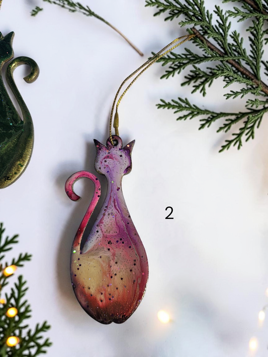 Pink mid century retro cat ornament handmade with resin and wood on a white background with Christmas lights and boughs 