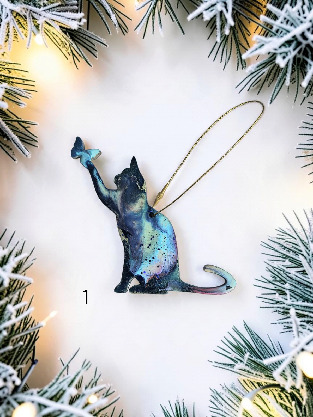 Playful cat and butterfly colorful resin handmade Christmas ornament on white background with Christmas lights 