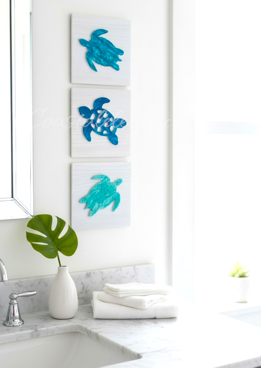 Three blue turtle sculptures on a white wall above a sink with a green leaf and white vase.